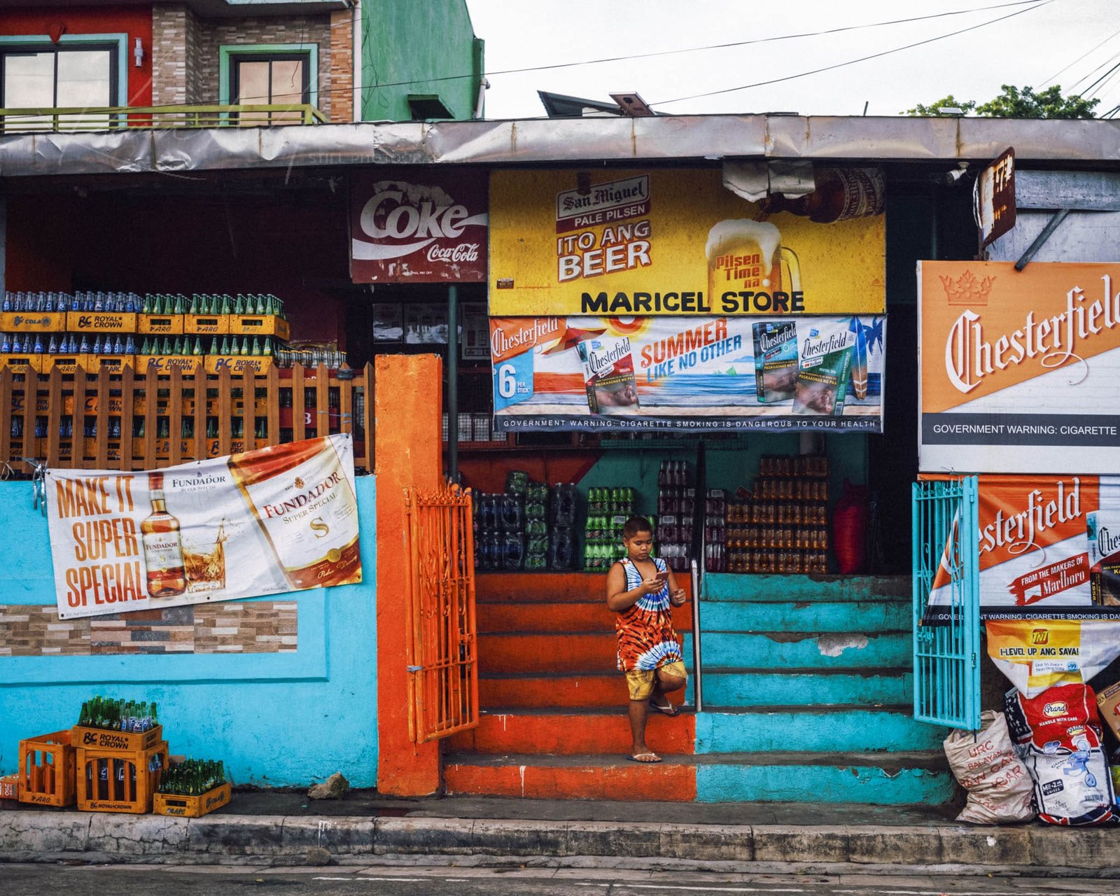 Colorful Tagaytay store with advertisements and local boy in urban setting.