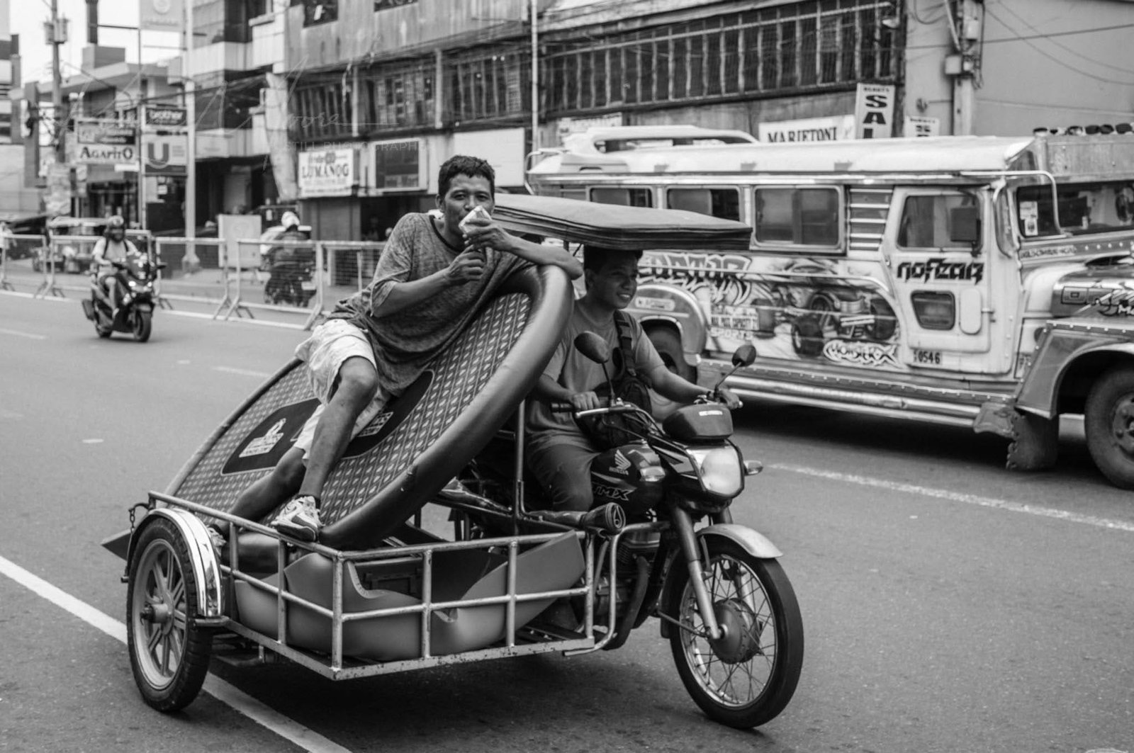 Motorcycle with recliner sidecar and mattress on busy Philippine street.