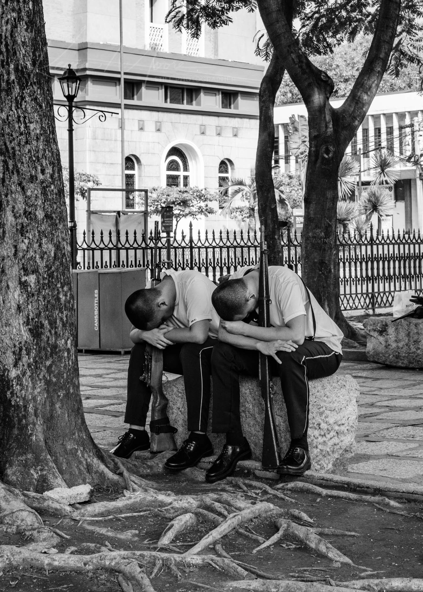 Two men in military attire rest thoughtfully in an urban park setting.