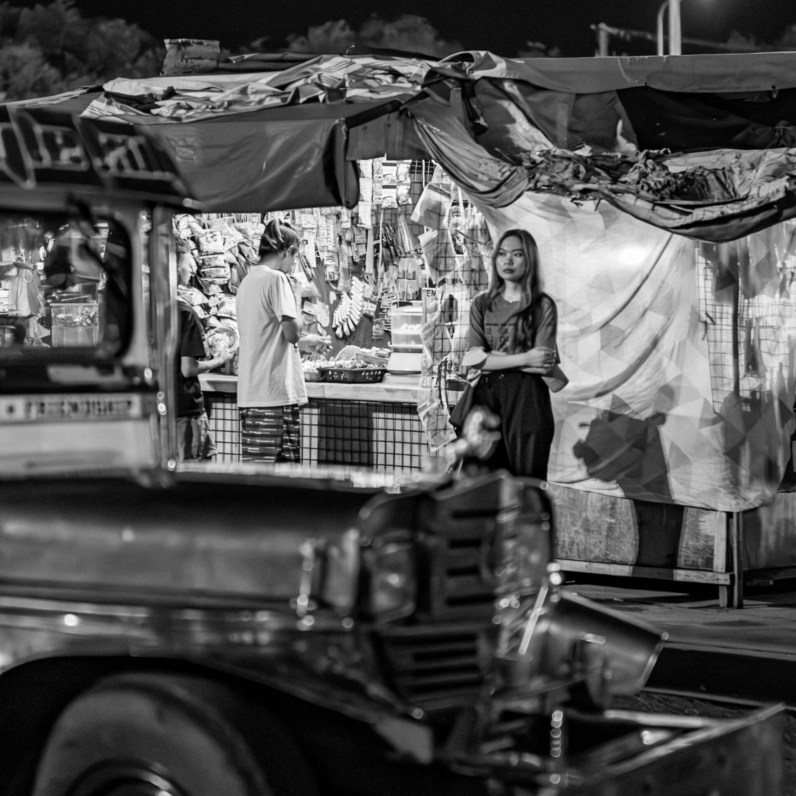 Vibrant night market scene with bustling local vendors and iconic jeepney in monochrome.