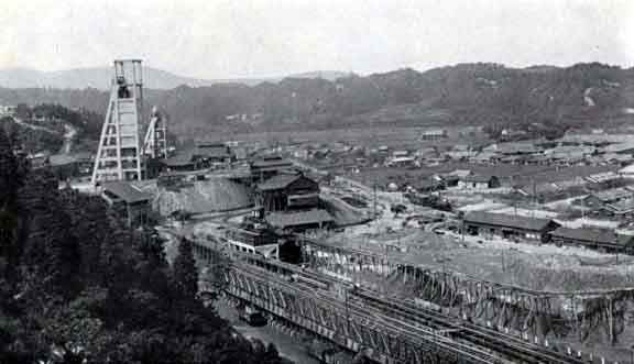 Historical Yoshima mining town with industrial structures and natural backdrop.