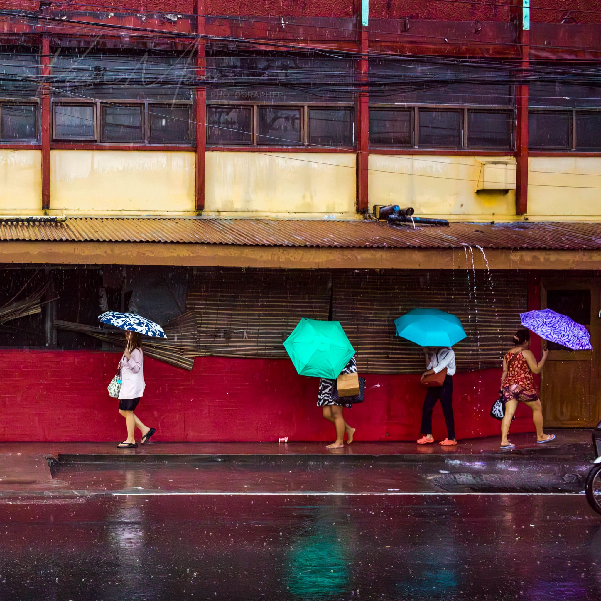 Rainy urban scene with colorful umbrellas and vibrant building facade.