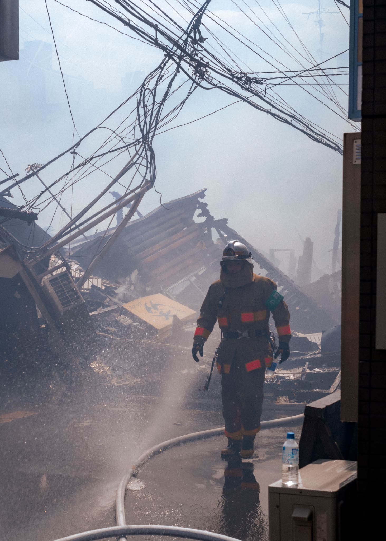 Japanese Firefighter exiting collapsed building amid emergency rescue efforts.
