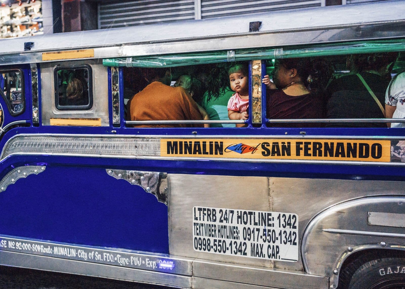 Colorful jeepney in Philippines with passengers during dawn or dusk.