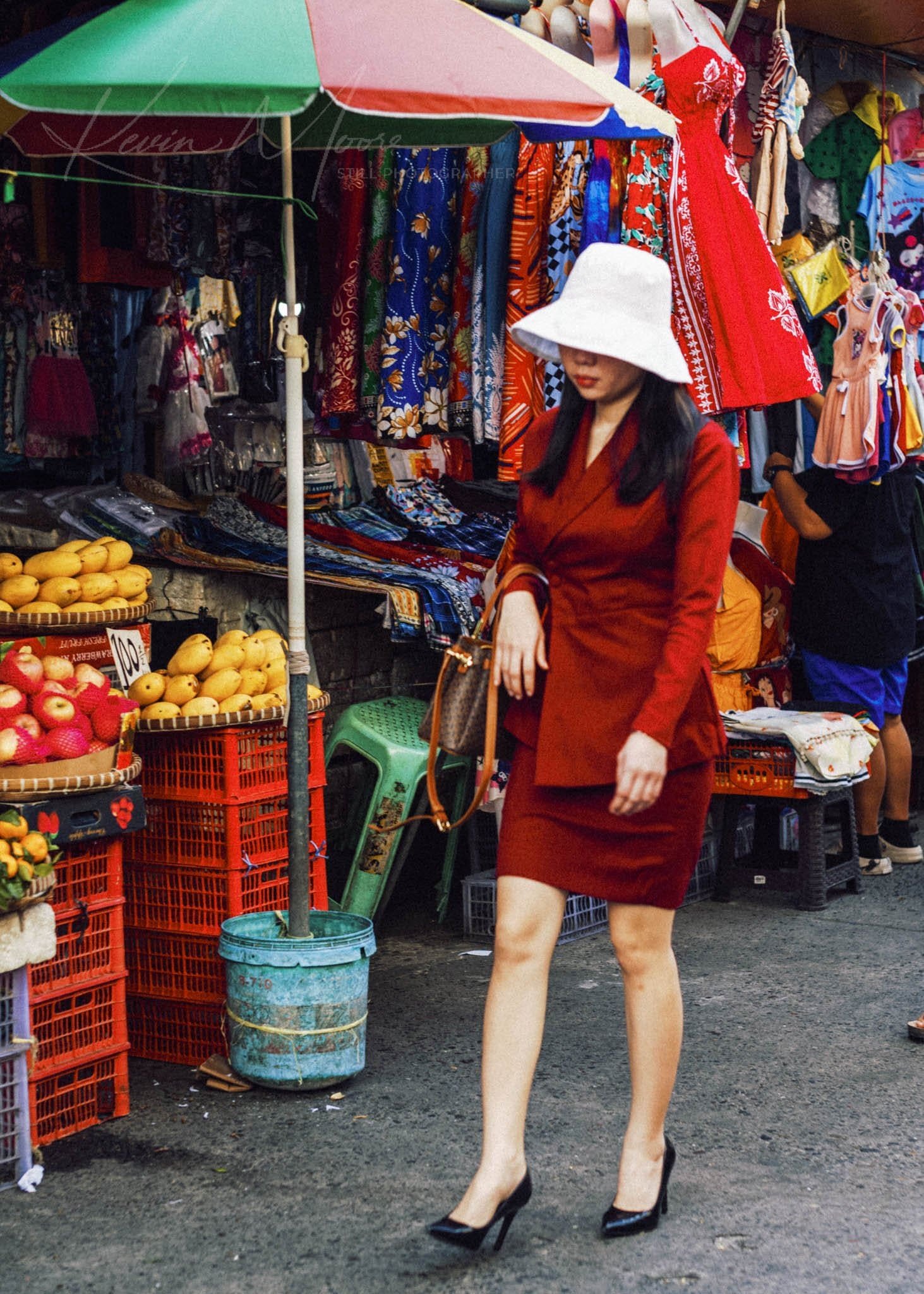 Woman in red dress shops at vibrant Philippine market.